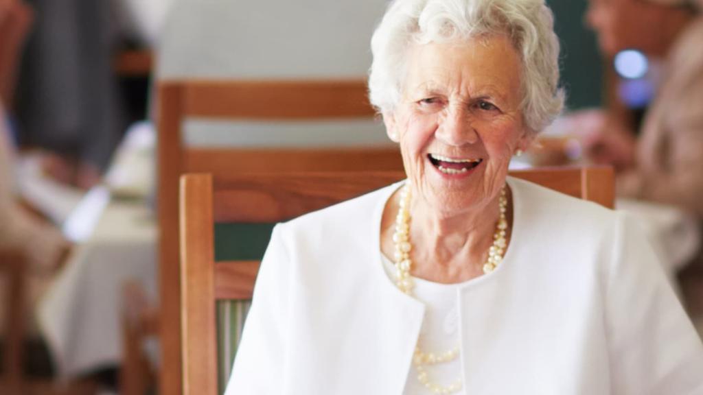 Smiling older lady eating with friends